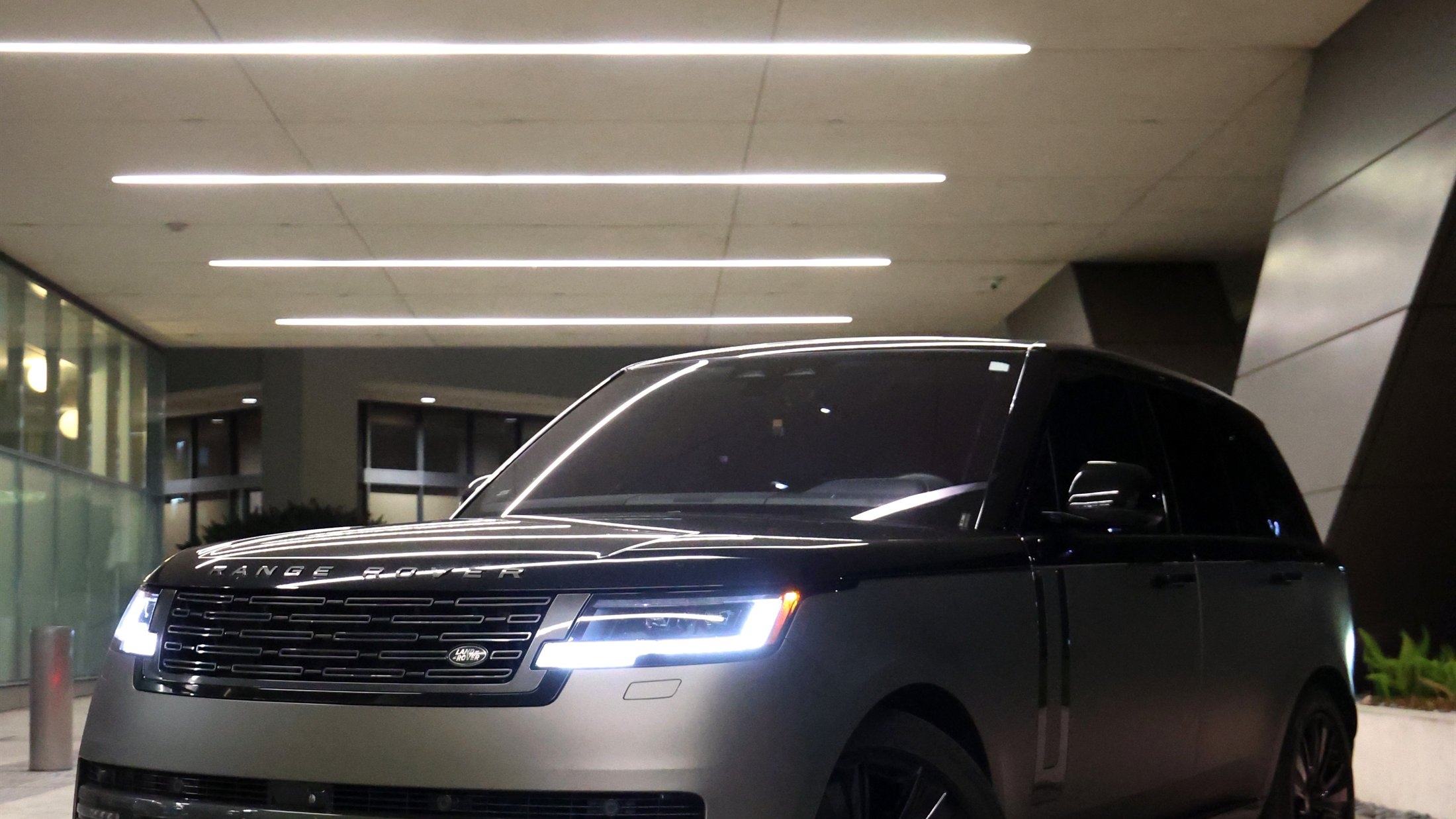 Range Rover lit from above in a modern parking structure at night
